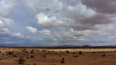 Volando-Sobre-Las-Hermosas-Tierras-Secas-Del-Desierto-De-Mojave-En-California-Con-Montañas-A-Lo-Lejos-Y-La-Luz-Del-Sol-Brillando-En-Un-área-Particular---Toma-Aérea-Baja