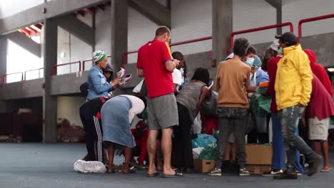 Personas-Sin-Hogar-Recibiendo-Folletos-Detrás-Del-Estadio-En-George,-Western-Cape,-Sudáfrica