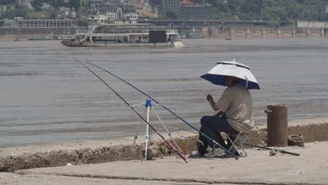 Hombre-Asiático-De-Mediana-Edad-Pescando-Junto-Al-Río