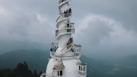 Mehrere-Touristen-Gehen-Die-Schöne-Schmale-Wendeltreppe-Hinauf-Zur-Spitze-Des-Hohen-Weißen-Ambuluwawa-Turms,-Während-Der-Hintergrund-In-Sri-Lanka-Von-Dicken-Wolken-Umhüllt-Ist