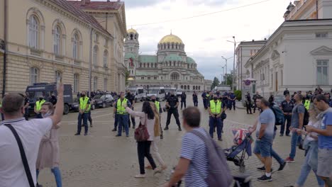 People-marching-against-the-government-after-a-corruption-scandal,-while-the-police-is-guarding-the-parliament