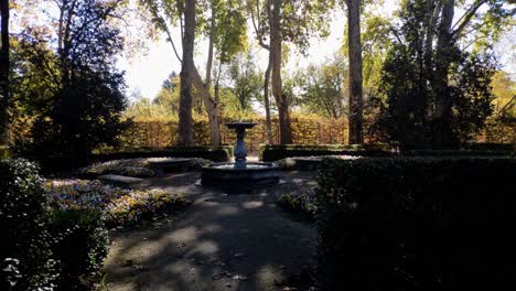 Still-shot-of-a-small-fountain-surrounded-by-stone-benches-at-Capricho-Park-in-Madrid,-Spain