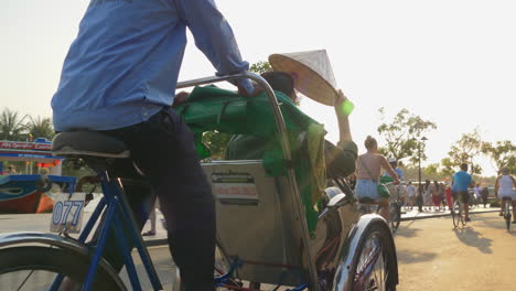 Una-Toma-De-Seguimiento-Detrás-De-Un-Turista-En-Un-Transporte-De-Alquiler-De-Bicicletas-Conduciendo-Por-La-Ciudad-De-Hoi-An-En-Vietnam