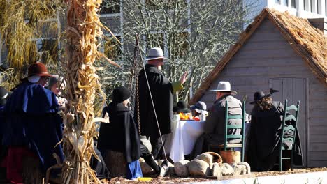 Authentic-Pilgrims-on-a-large-parade-float-with-a-Thanksgiving-Dinner-and-a-farmhouse-waving-to-people-and-rolling-down-the-main-street-during-the-Thanksgiving-Parade-2019-in-Plymouth,-Massachusetts