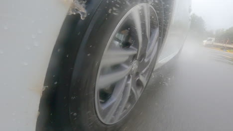 Primer-Plano-De-La-Rueda-De-Un-Peugeot-208-Blanco-Girando-Rápidamente-Salpicando-Agua-Sobre-La-Carrocería