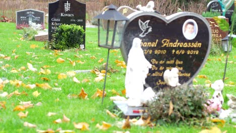 A-grave-belonging-to-a-young-boy-on-an-autumn-day-in-Kviberg-Cemetery-in-Gothenburg,-Sweden---Focus-and-panning-shot