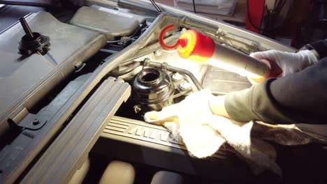 White-male-cleaning-around-power-steering-pump,-static