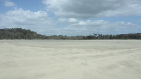 Dron-Bajo-Volando-Rápidamente-A-Través-Del-Lecho-De-Un-Lago-Seco-Y-Luego-Elevándose-Sobre-Matorrales