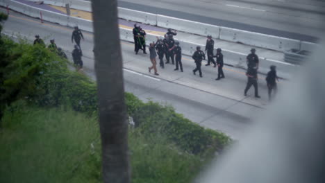 Un-Grupo-De-Policías-Antidisturbios-Caminan-A-Un-Hombre-Con-Las-Manos-En-Alto-Por-La-Autopista-110-Durante-Una-Protesta-En-El-Centro-De-La-Ciudad.