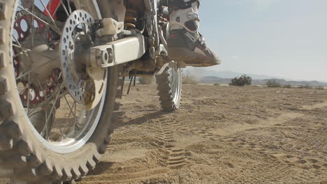 Cámara-Lenta:-Una-Patada-De-Motociclista-Honda-Arranca-Su-Bicicleta-Y-Se-Prepara-Para-Despegar-En-El-Desierto