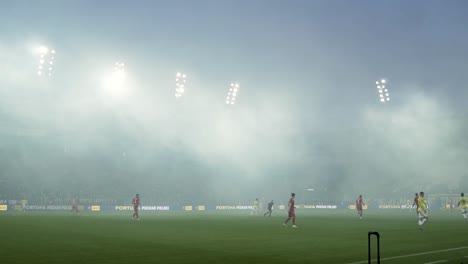 Rauch-Im-Fußballstadion-Während-Des-Spiels,-Flutlicht,-Spieler-Und-Rauchbomben