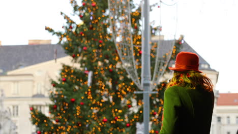 Artista-Femenina-Cantando-En-El-Escenario-Durante-Una-Actuación-Navideña-Vestida-De-Verde-En-El-Fondo-Con-Adornos-Navideños-Y-Un-árbol-Verde-En-El-Mercado-De-La-Plaza-Verde-Capturado-En-Cámara-Lenta-De-4k-60fps