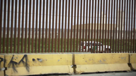 From-Tijuana-Mexico,-a-Border-Patrol-truck-drives-along-the-other-side-of-the-border-fence