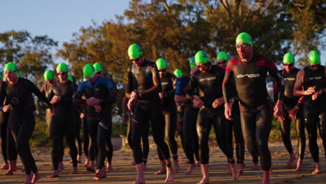 4K-Slow-Motion-Athletes-In-Swimwear,-Goggles-And-Swim-Cap-Running-Over-Starting-Line-Of-Race