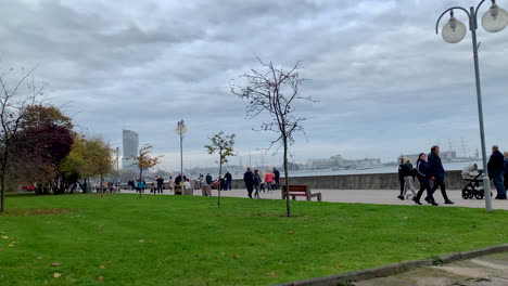 Menschen-Gehen-Auf-Dem-Strandboulevard-Spazieren,-Herbstspaziergang-An-Der-Küste,-Zeitlupe