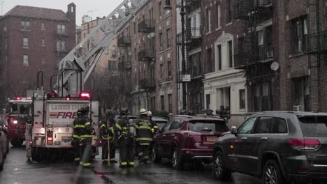 Grupo-De-Bomberos-Del-FDNY-Evaluando-Un-Edificio-En-Una-Cuadra-Nevada-De-Brooklyn---Plano-Amplio