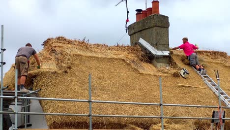 Thatchers-at-work-on-roof-on-a-cottage-near-Canterbury,-Kent,-UK