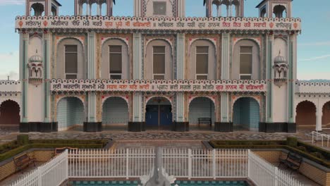 Drone-4K-Footage-front-facade-of-Sikh-temple-with-beautiful-and-elaborate-sculpture-and-symmetrical-architecture-in-the-middle-of-a-farmland