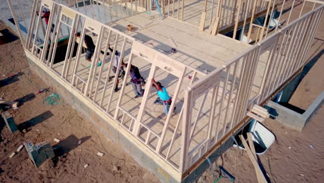 A-drone-shot-floating-around-the-construction-framers-putting-up-walls-on-a-new-home-in-the-process-of-being-built