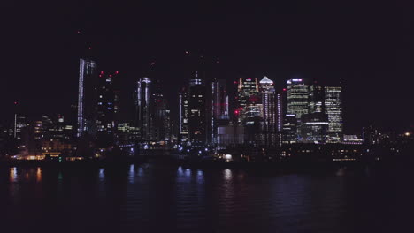 Aerial-View-of-London-Financial-District-at-night-from-the-river-Thames