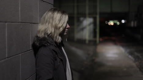 Girl-leans-against-a-wall-in-an-alley-at-night