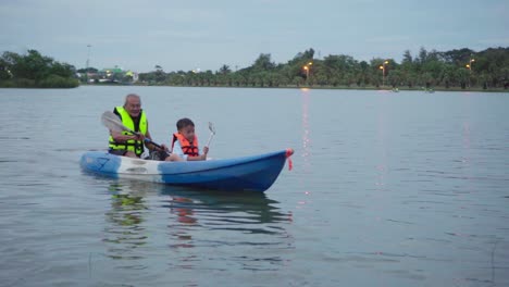 Un-Anciano-Y-Su-Joven-Nieto-Haciendo-Kayak-En-Un-Lago-En-Tailandia