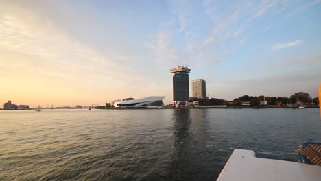 Slow-motion-footage-of-ferry-crossing-at-IJ-River-during-sunset,-Amsterdam,-Netherlands