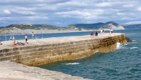 Eine-Gruppe-Von-Jungen-übt-Von-Der-Hafenmauer-Aus-Das-Springen-Ins-Meer