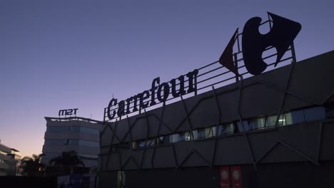 Pan-left-shot-of-Carrefour-brand-logo-at-sunset