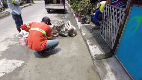 Foremen-wearing-safety-reflective-vests-used-their-shovel,-mixed-cement,-and-demolition-hammer-to-perform-excavation-beside-the-road-gutter-to-install-new-water-piping-from-the-main-water-line