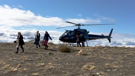 Tourists-exit-a-helicopter-on-a-snow-capped-peak-in-Queenstown-New-Zealand