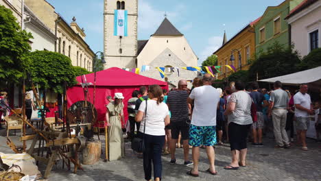 Slow-motion-lateral-shot-of-people-in-the-Medieval-reenactment-festival-with-tents-in-the-main-square,-Preludij-festival-in-Slovenj-Gradec-slovenia