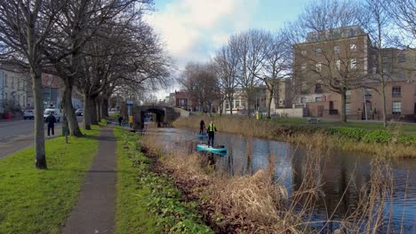 4K-Ansicht-Von-Zwei-Männern,-Die-Im-Frühjahr-Auf-Dem-Grand-Canal-In-Dublin-An-Bord-Gehen