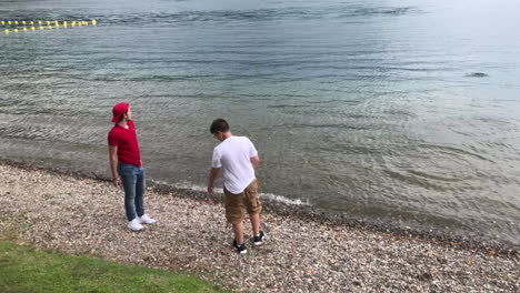 Family-enjoying-a-summer-day-on-the-beach-throwing-a-flat-stone-across-water