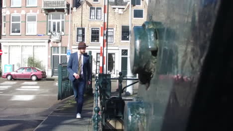 An-elegant-man-in-dandy-style-with-beard-walks-on-a-bridge-in-Amsterdam