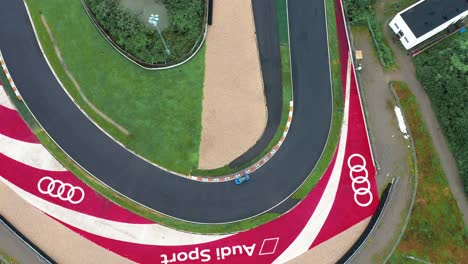 Top-down-aerial-view-of-lotus-sports-car-passing-Audi-logo-on-a-race-track-in-Ningbo-circuit-in-china