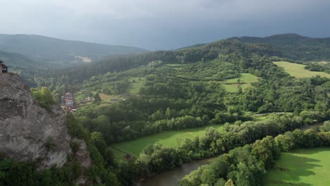 Reveal-of-the-famous-Orava-Castle-in-Slovakia,-situated-on-top-of-a-thin-hill-next-to-the-river-Orava,-from-a-drone-view-on-a-sunny-and-cloudy-day