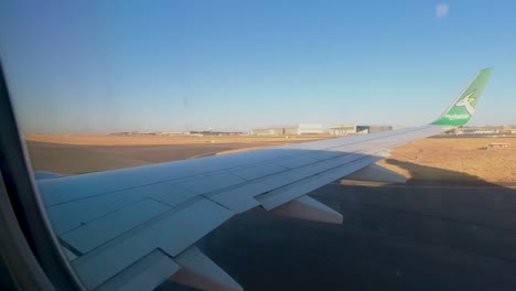 FlySafair-jet,-wing-view-window-seat,-taxiing-from-OR-Tambo