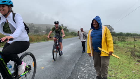 Cyclists-waving-at-pedestrians-on-road,-continuous-shot