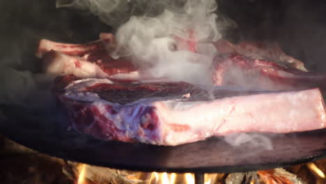 Beef-steaks-grilling-on-a-cast-iron-plate,-beef-steak-in-smoke-from-wood-fire