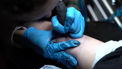 The-tattoo-artist-is-making-a-tattoo-on-a-man's-hand