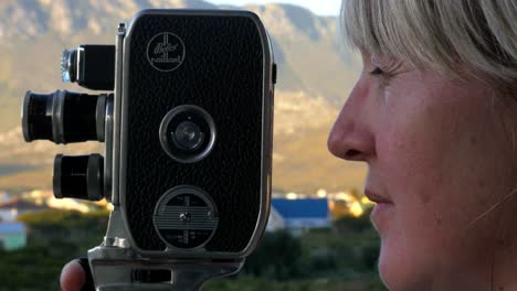 A-young-lady-filming-and-panning-with-a-vintage-8mm-film-camera-close-up