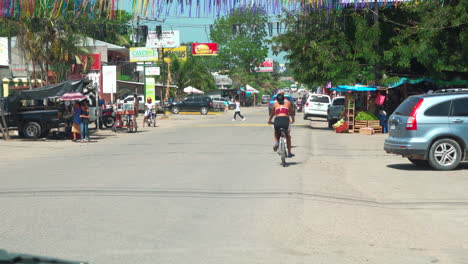 A-woman-rides-her-bike-down-a-quiet-street-in-the-afternoon-sun