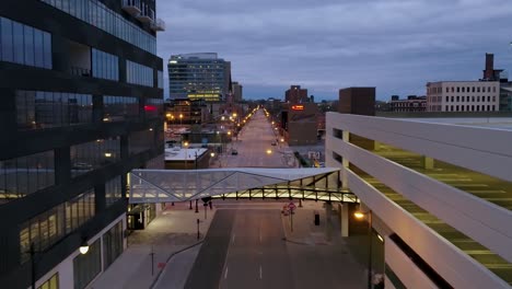 Aerial-drone-view-flying-in-middle-of-lit-buildings-and-over-calm-streets-of-Columbus,-USA