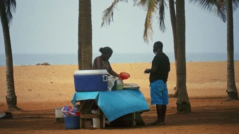 Woman-selling-food-at-beach-in-Lomé,-Togo,-West-Africa