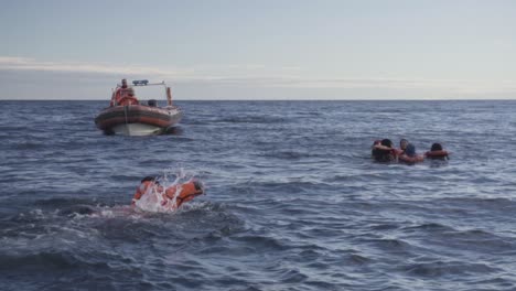 Seemann-Schwimmt-Im-Patagonischen-Meer-Auf-Das-Rettungsboot-Zu,-Während-Eine-Gruppe-Von-Männern-Während-Einer-Nautischen-Ausbildung-Im-Wasser-Schwimmt---Zeitlupe