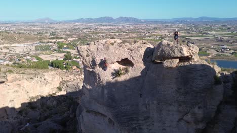 Sportsmen-rock-climbing-aerial-view-of-sportsman-rapelling-mountain-in-La-Panocha,-el-Valle-Murcia,-Spain-woman-rapel-down-a-mountain-climbing-a-big-rock