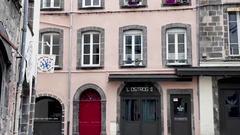 Arquitectura-Francesa-De-Casas-De-La-Ciudad-Con-Ventanas-Arqueadas-Y-Jardineras,-Puertas-De-Entrada-Rojas-Y-Una-Pequeña-Tienda-En-La-Planta-Baja.