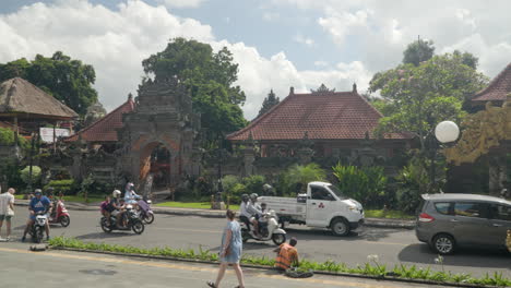 -Außenansicht-Des-Ubud-Palastes-Mit-Starkem-Verkehr-Auf-Der-Straße-Im-Zentrum-Der-Stadt,-Balinesischer-Lebensstil---Zeitlupen-Schwenk