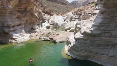 Person-swimming-in-clear-water-of-socotra-canyon-during-sunny-day-in-Yemen